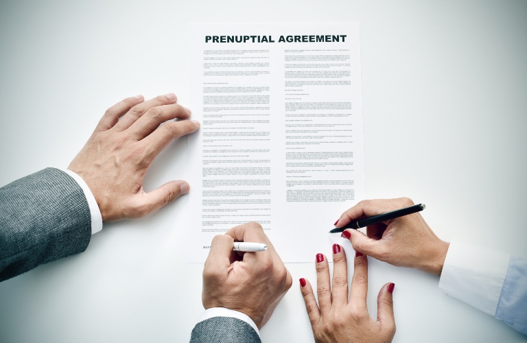 man and a woman sign a prenuptial agreements