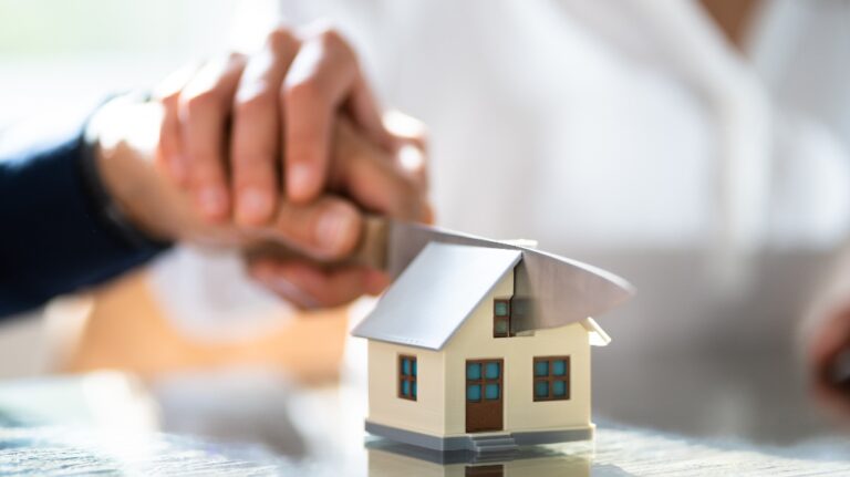 man and a woman cut a model of a house
