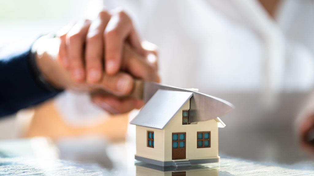 man and a woman cut a model of a house