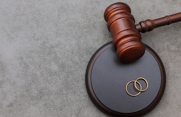 Judge gavel and wedding rings on concrete stone grey background